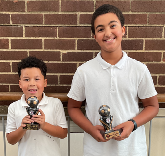 image of 2 boys with football trophies